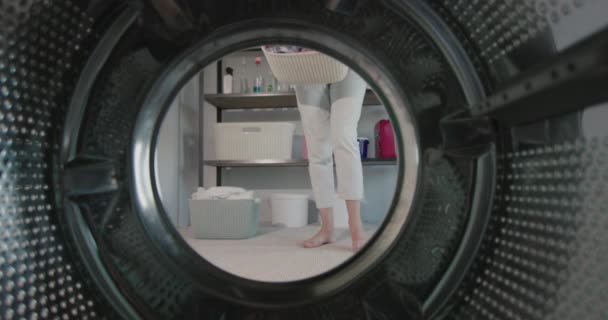 Kobieta wylewa na podłogę dużo kolorowego prania do prania. Widok z pralki. Filmik o zwolnionym tempie — Wideo stockowe