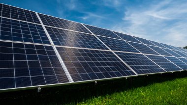 Yeşil çayır üzerindeki güneş enerjisi panelleri bulutlu mavi gökyüzüne karşı