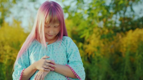 Uma criança com cabelo rosa desfruta de um relógio inteligente. Conceito de Segurança Infantil e Controle Parental — Vídeo de Stock