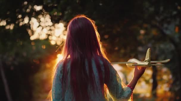 Η σιλουέτα ενός κοριτσιού με ένα αεροπλάνο παιχνίδι. Παίζοντας στο ηλιοβασίλεμα στο δρόμο — Αρχείο Βίντεο