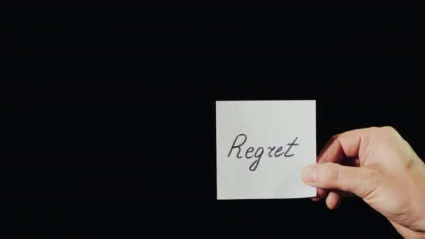 El hombre quema un papel con la inscripción Regret — Vídeo de stock