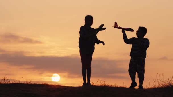 Två barn som har roligt vid solnedgången - leka flygplan — Stockvideo