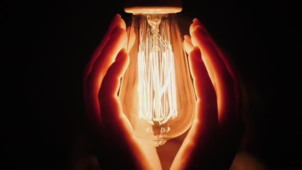 Duas mãos perto de uma lâmpada elétrica no escuro — Vídeo de Stock