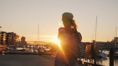 Aktif kadın marinada gün doğumunda seviniyor. Öne doğru koşuyor, ellerini kaldırıyor. Bergen 'de gün doğumu