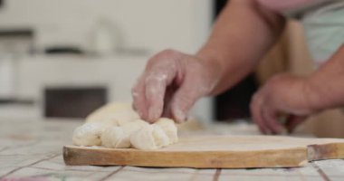 Yaşlı bir kadın, eski bir odun sobasının arka planında un ürünleri yapıyor..