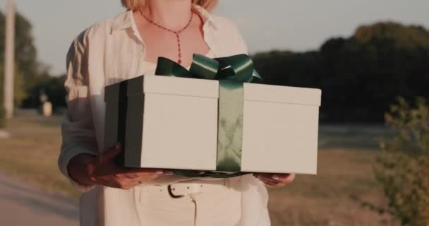 Egy magabiztos nő sétál az utcán egy ajándékkal a kezében. — Stock videók