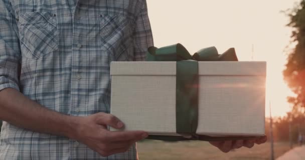 Een man houdt een mooi verpakt doosje met een geschenk vast — Stockvideo