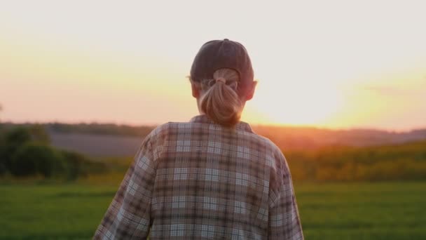 Жінка-фермерка проходить через мальовниче поле на заході сонця — стокове відео