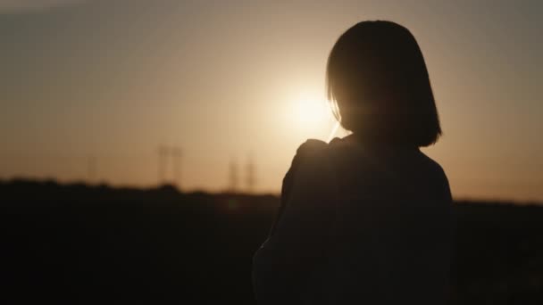 Silhueta de uma mulher bebendo um coquetel de um tubo ao pôr do sol — Vídeo de Stock
