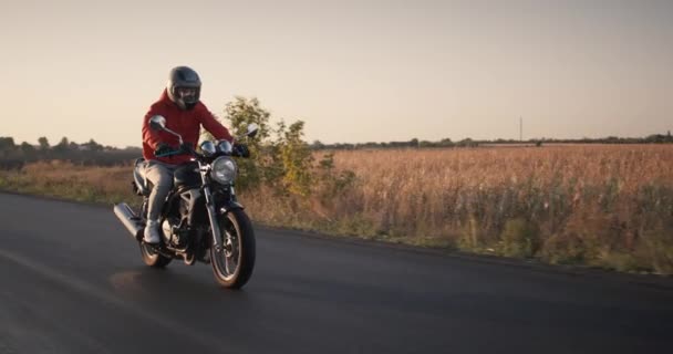 Motociclista cavalca su una strada poco profonda, poi guida fuori dal telaio — Video Stock