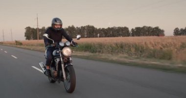 Motosikletli gün batımından önce mısır tarlaları boyunca gezer.