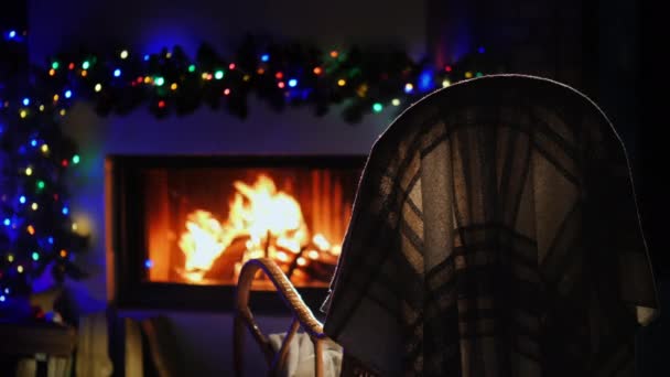 Un fauteuil à bascule se tient devant une cheminée décorée pour Noël et le Nouvel An. — Video