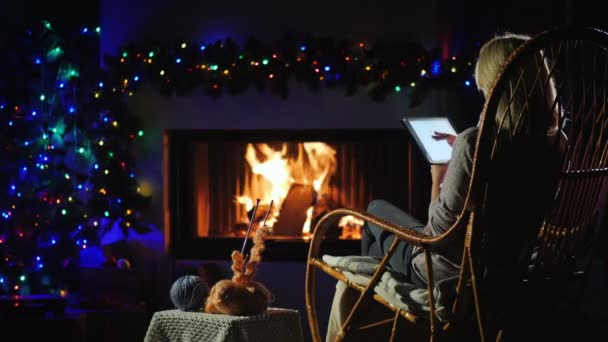 Young woman resting by the fireplace, using a tablet — Stock Video