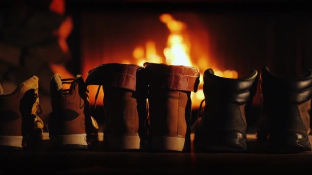 Natte winterschoenen staan bij de open haard, het comfort van een warm huis — Stockvideo