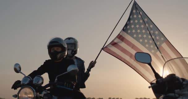 Biker with girlfriend sits on motorcycle, woman holds U.S. flag — Stock Video