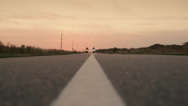 Silhouettes de deux motocyclistes passent rapidement devant la caméra sur l'autoroute contre le soleil couchant — Video