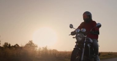 Motosikletliler gün batımında bir kır yolunda geziyorlar.