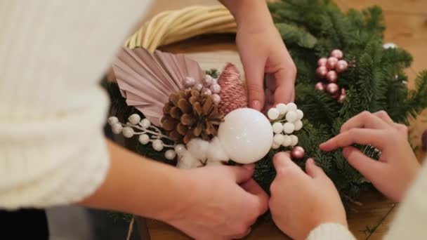 Çocuklu bir kadın Noel çelenginde mücevher tamir ediyor. — Stok video