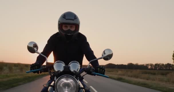 Молодой байкер едет по шоссе в лучах заходящего солнца — стоковое видео