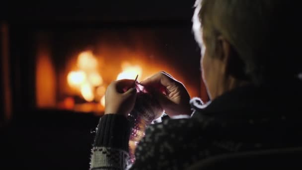 Mujer artesanía junto a la chimenea, teje ropa de abrigo — Vídeos de Stock