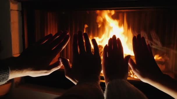 Jong stel verwarmt hun handen bij de open haard, romantische avond samen — Stockvideo