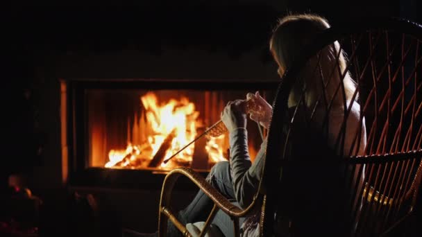 Vrouw doet handwerk zitten bij de open haard, winter vrije tijd — Stockvideo