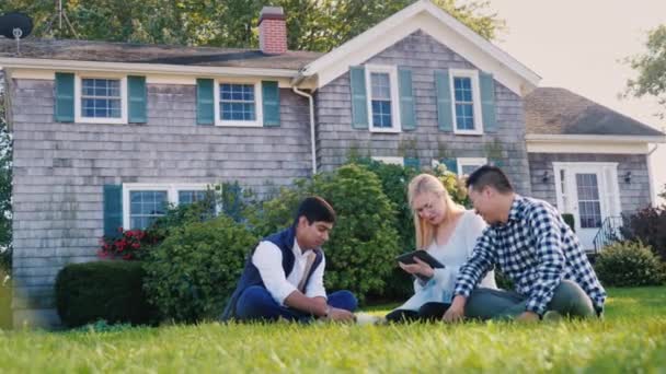 A group of friends relaxes in the backyard of the house, beside their beloved dog — Stock Video