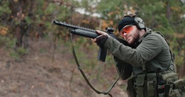 Kamuflaj elbiseli bir adam tüfekle ateş ediyor. Yavaş çekim videosu