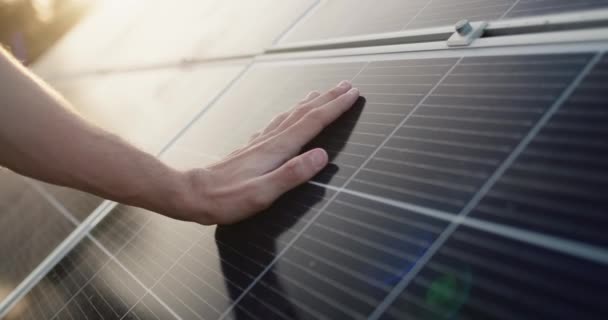 Een man houdt zijn hand boven het oppervlak van de zonnepanelen. — Stockvideo