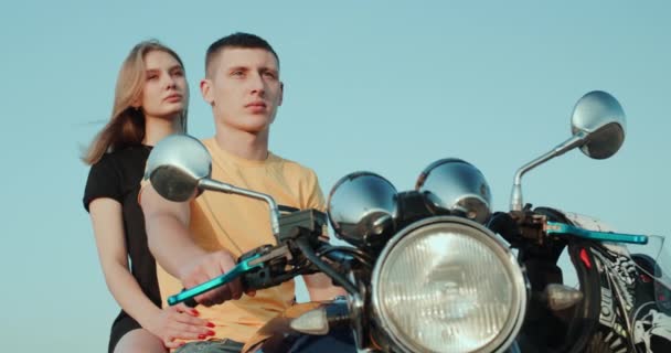 Un ragazzo e una ragazza sono seduti su una moto, guardando in lontananza — Video Stock