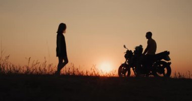Genç bir kadının silueti, motosiklet süren adama gider.