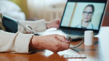 Kıdemli kadın kamerayla doktora danışıyor, kan basıncını ölçüyor.