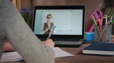 Kız evde internetten öğreniyor, dizüstü bilgisayardaki öğretmeni ders veriyor.