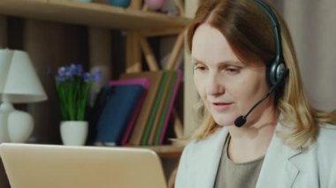 Kadın evden gelen müşterilerle iletişim kuruyor, kulaklıkla konuşuyor. Merkez Ofis