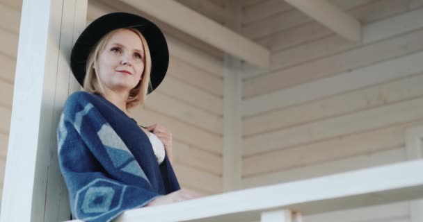 Stylische Frau mit Hut auf der Terrasse ihres Hauses — Stockvideo