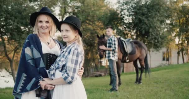 Mãe com filha e no plano de saída de um jovem com um cavalo - sessão de fotos com cavalos e turismo verde — Vídeo de Stock