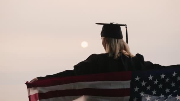 Bachelor in un mantello e un berretto con una bandiera americana sulle spalle — Video Stock