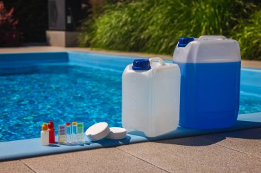 Havuz bakımı malzemeleri, sıvı kimyasal kutular, klor tabletleri ve güneşli bir günde havuzun kenarına bırakılan şişelerin test kiti. Yüksek kalite fotoğraf