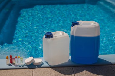 Havuz temizleme seti, test şişeleri, klor tabletleri ve güneşli yaz bakımı sırasında temiz bir yüzme havuzunun kenarında düzenlenmiş mavi kimyasal kaplar. Yüksek kalite fotoğraf