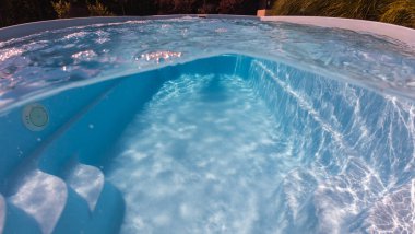 Su altında ve yukarıdaki mavi yüzme havuzu kıvrımlı merdivenler ve yerde ve duvarlarda güneş ışığı yansımaları, sükunet ve rahatlığı çağrıştırıyor. 