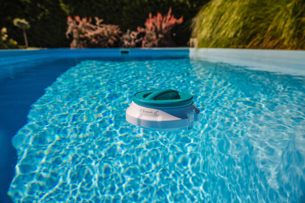 Плавающий дозатор хлора с термометром, дрейфующим в прозрачном открытом бассейне, помогает поддерживать чистую воду и безопасные условия плавания. Высокое качество фото