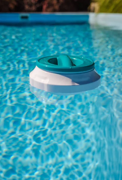 Yüzen klor dağıtıcısı temiz mavi havuz suyunda sürükleniyor, düzenli bakım ve su dezenfeksiyonu için kullanılıyor. Yüksek kalite fotoğraf