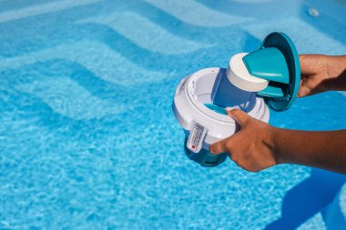 Eller temiz ve güvenli yüzme suyu için yüzen havuz makinesine klor tableti yerleştiriyor. Yüksek kalite fotoğraf