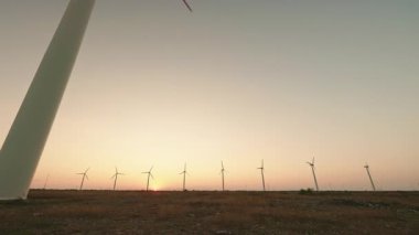 Gün batımında ufukta birden fazla rüzgar türbini olan panoramik manzara yenilenebilir enerji ve sürdürülebilir gelişimi vurguluyor. Yüksek kalite 4k görüntü