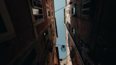 Roma 'nın dar sokaklarında yüksek konut binaları, kablolar ve yukarıdan yayılan lambalar, yürüyen bir perspektiften gökyüzü manzarası ile çekiliyor.. 