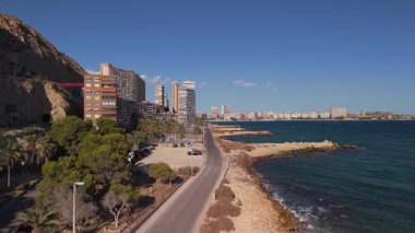 İspanya, Alicante 'deki Cabo de la Huerta boyunca sahil yolu ve konut binaları. Kayalık kıyı şeridi, palmiye ağaçları ve Akdeniz manzaralı. Yüksek kalite 4k görüntü