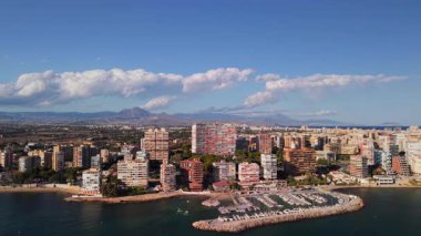İspanya 'nın Alicante kentindeki Albufereta bölgesinin havadan görünüşü, marina, konut binaları ve dramatik bulutların altında dağlar. Yüksek kalite 4k görüntü