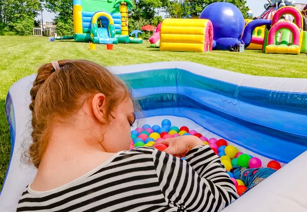 Инвалид ребенок-инвалид расслабляется в бассейне с большим количеством игрушечных шариков . — стоковое фото