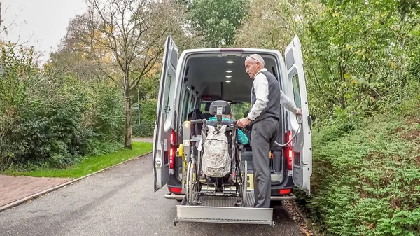 Un retraité âgé aidant au transport des personnes handicapées Images De Stock Libres De Droits