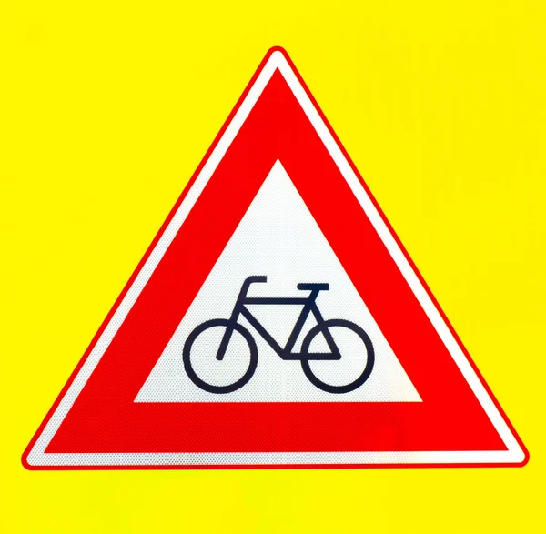Um triângulo vermelho cuidado com o sinal de aviso dos ciclistas em um fundo amarelo — Fotografia de Stock